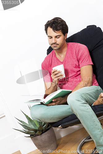 Image of Man Sitting on Chair with Book and a Drink