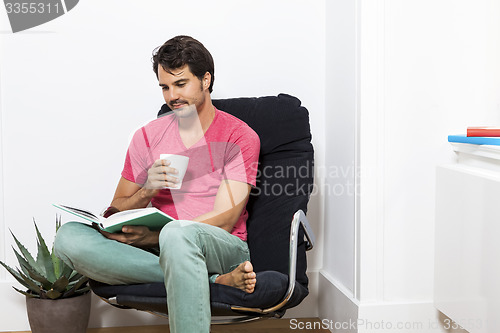 Image of Man Sitting on Chair with Book and a Drink