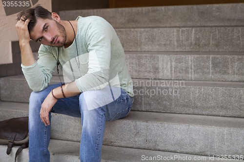 Image of Casual  young man sitting on steps