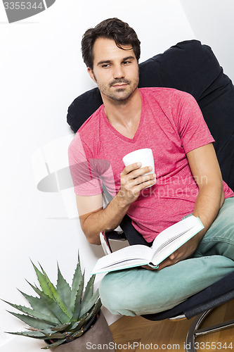 Image of Man Sitting on Chair with Book and a Drink