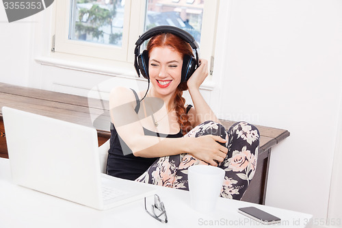 Image of Happy Young Woman Listening Music In her Room