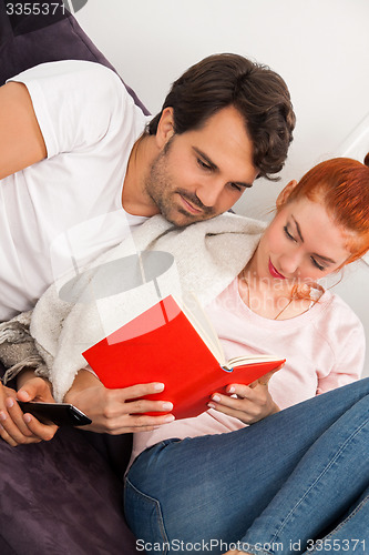 Image of Sweet Couple Resting on Couch While Reading a Book