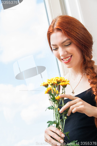 Image of Thoughtful Woman with Flowers Leaning on Window