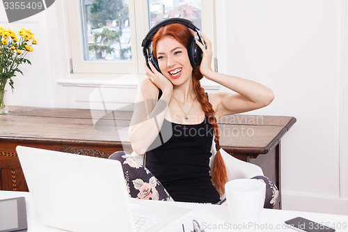Image of Happy Young Woman Listening Music In her Room