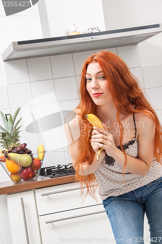 Image of Happy Woman Holding Banana Dancing in the Kitchen