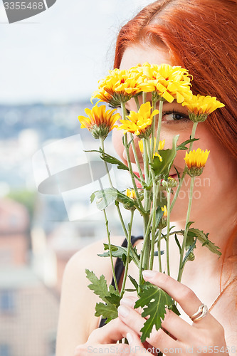 Image of Thoughtful Woman with Flowers Leaning on Window