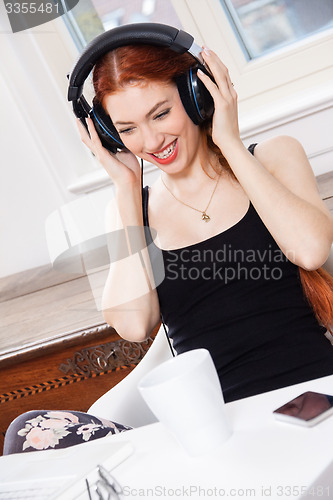 Image of Happy Young Woman Listening Music In her Room