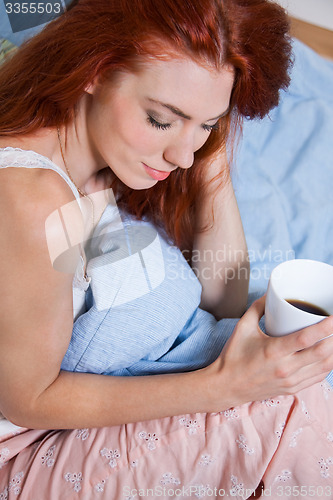 Image of Pensive Woman Having an Early Coffee at her Bed