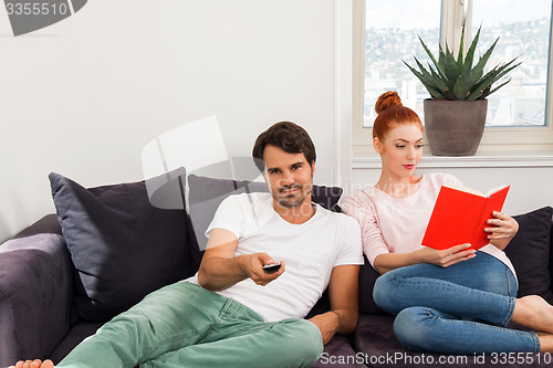 Image of Sweet Couple Resting on Couch While Reading a Book