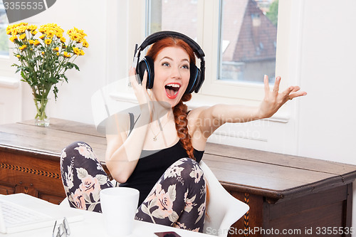 Image of Happy Young Woman Listening Music In her Room