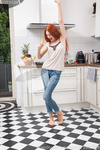 Image of Happy Woman Holding Banana Dancing in the Kitchen