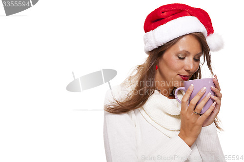 Image of Cold young woman in a Santa hat sipping coffee tea