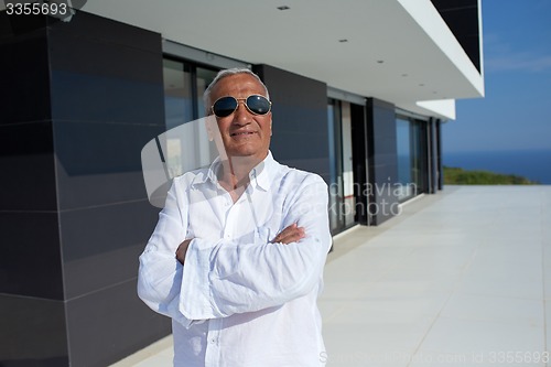 Image of senior man in front of modern home