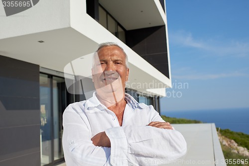 Image of senior man in front of modern home