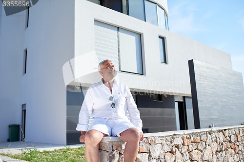 Image of senior man in front of modern home