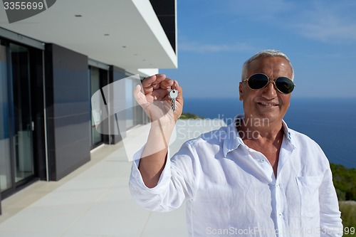 Image of senior man in front of modern home