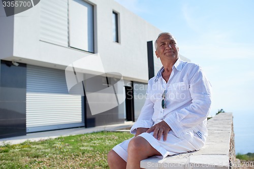 Image of senior man in front of modern home