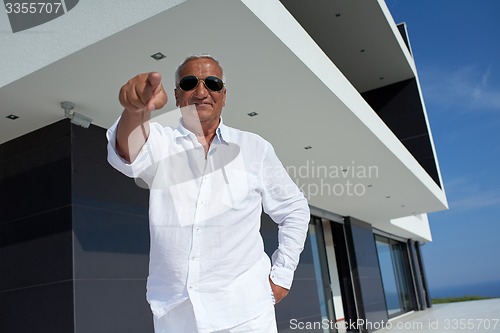 Image of senior man in front of modern home