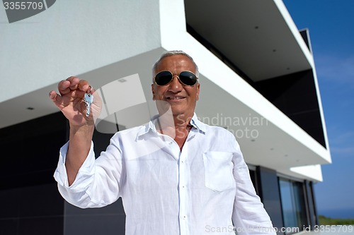 Image of senior man in front of modern home