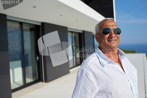 Image of senior man in front of modern home