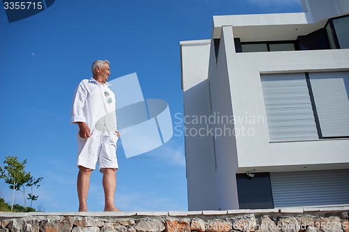 Image of senior man in front of modern home