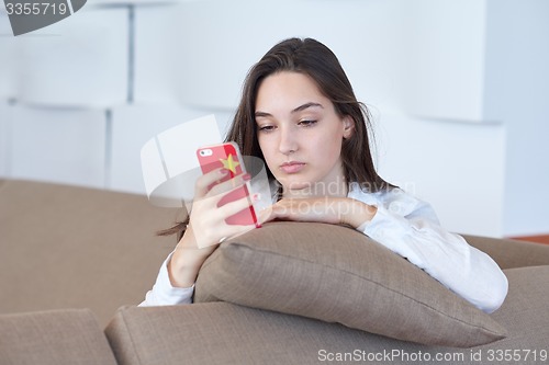 Image of young woman using cellphone at home