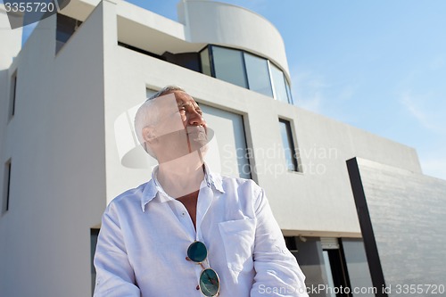 Image of senior man in front of modern home