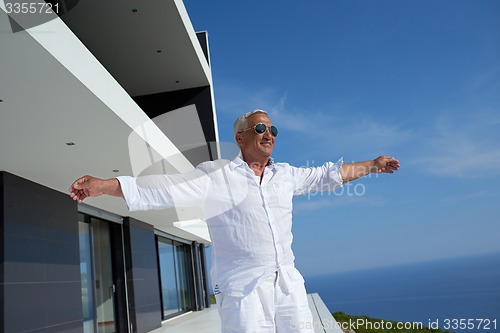 Image of senior man in front of modern home