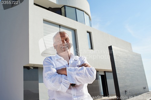 Image of senior man in front of modern home