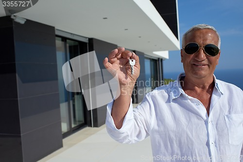 Image of senior man in front of modern home