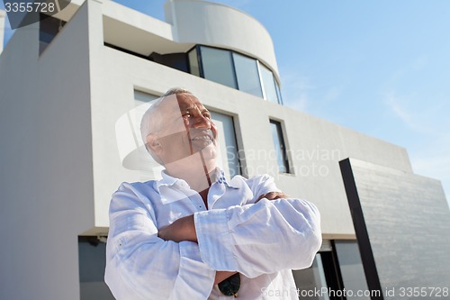 Image of senior man in front of modern home