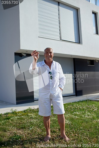 Image of senior man in front of modern home