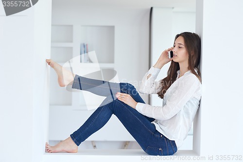 Image of young woman using cellphone at home