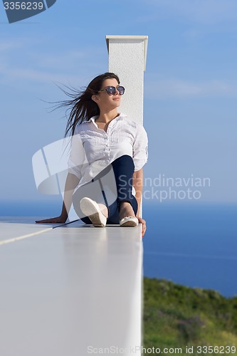 Image of relaxed woman in front of luxury modern home