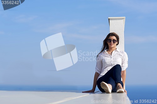 Image of relaxed woman in front of luxury modern home