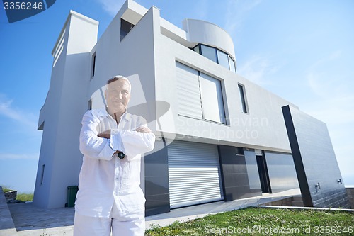 Image of senior man in front of modern home