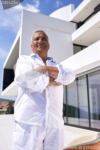 Image of senior man in front of modern home