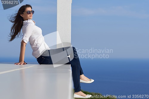 Image of relaxed woman in front of luxury modern home