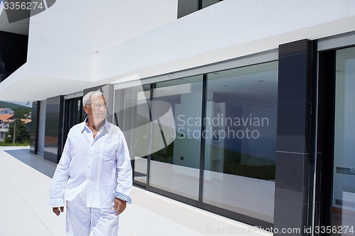 Image of senior man in front of modern home