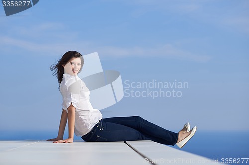 Image of relaxed woman in front of luxury modern home
