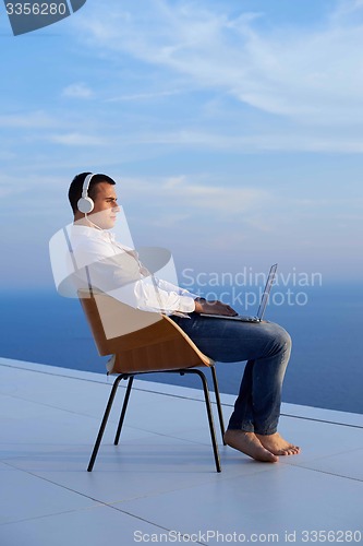 Image of relaxed young man at home on balcony