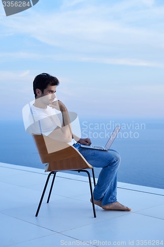 Image of relaxed young man at home on balcony