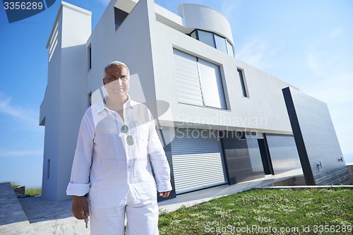 Image of senior man in front of modern home