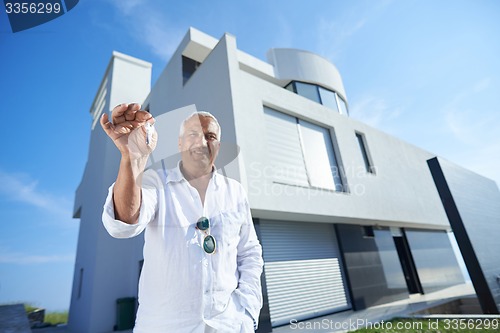 Image of senior man in front of modern home