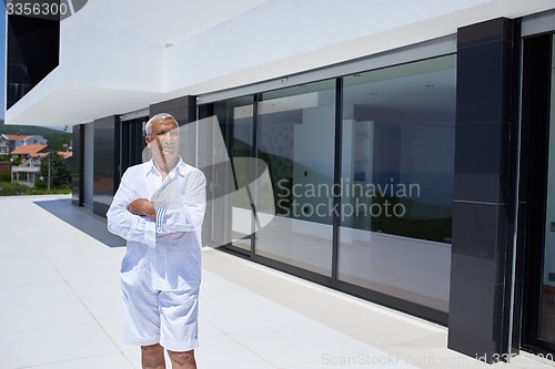 Image of senior man in front of modern home