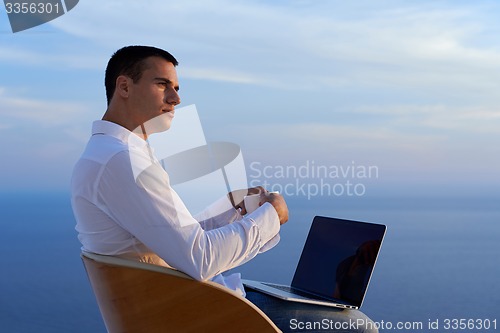 Image of relaxed young man at home on balcony