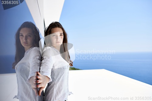 Image of relaxed woman in front of luxury modern home