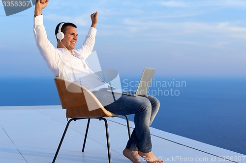 Image of relaxed young man at home on balcony