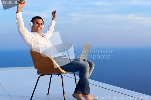 Image of relaxed young man at home on balcony