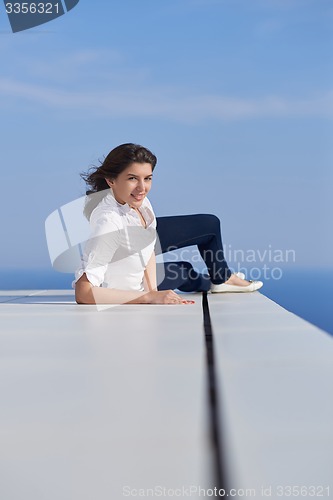 Image of relaxed woman in front of luxury modern home
